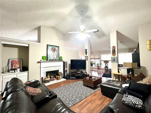 living room with lofted ceiling, a textured ceiling, hardwood / wood-style flooring, ceiling fan, and a fireplace