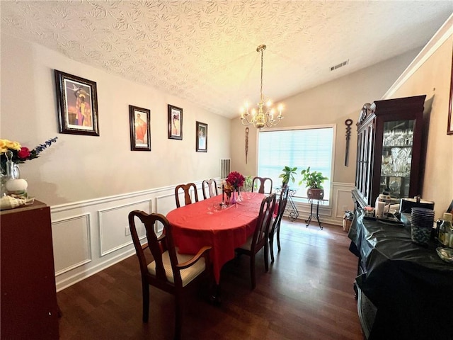 dining room featuring lofted ceiling, a textured ceiling, dark hardwood / wood-style floors, and a chandelier