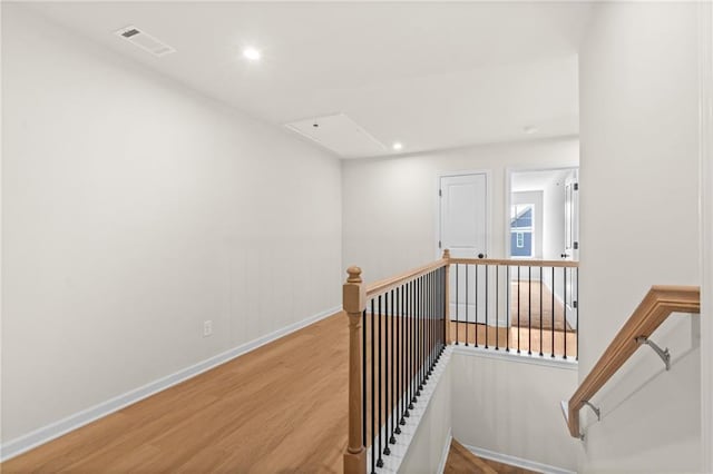 hallway with visible vents, baseboards, an upstairs landing, recessed lighting, and wood finished floors