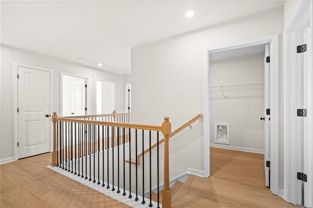 hallway with recessed lighting, light wood-type flooring, an upstairs landing, and baseboards