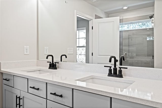 bathroom with double vanity, a shower stall, and a sink