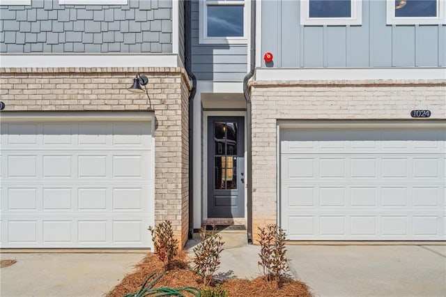 entrance to property featuring brick siding, driveway, and board and batten siding