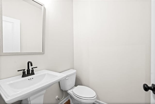 half bath with a sink, baseboards, and toilet