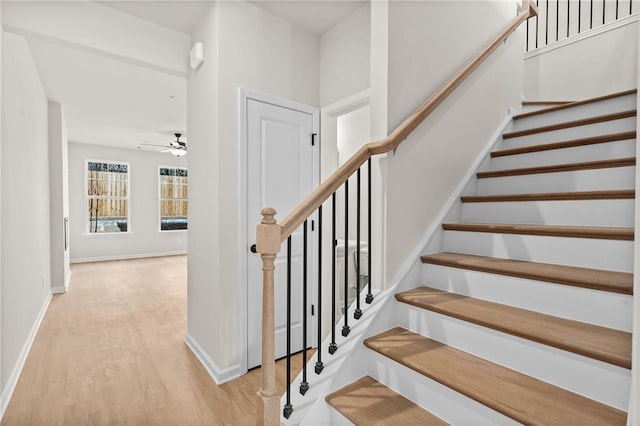 stairway with ceiling fan, baseboards, and wood finished floors