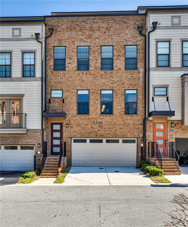 multi unit property featuring an attached garage, brick siding, and driveway