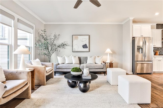 living room with a ceiling fan, crown molding, and wood finished floors