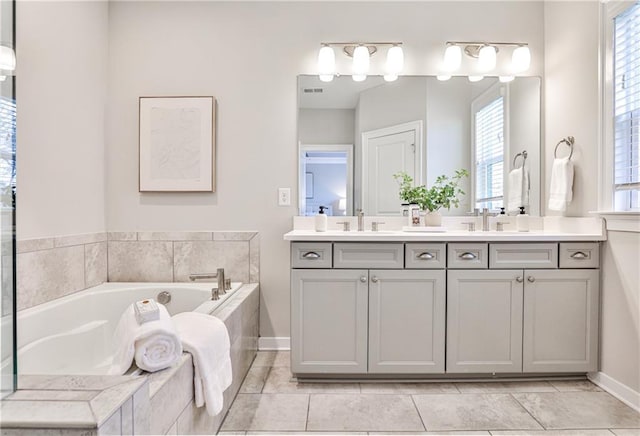 bathroom with a bath, visible vents, double vanity, and a sink