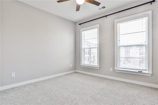 carpeted spare room featuring ceiling fan and baseboards