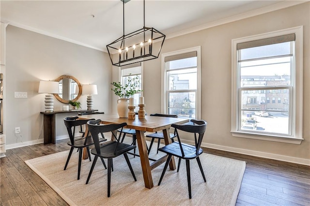 dining space featuring dark wood finished floors, crown molding, baseboards, and a chandelier