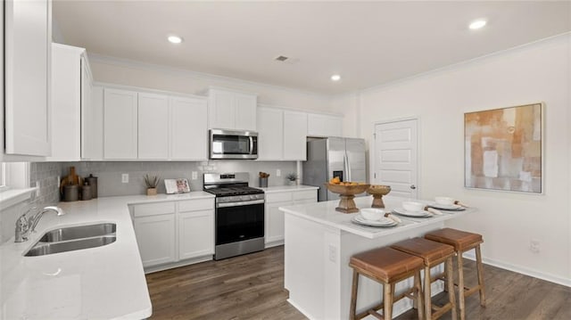 kitchen with appliances with stainless steel finishes, white cabinetry, sink, dark hardwood / wood-style floors, and a kitchen island