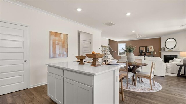 kitchen with crown molding, dark wood-type flooring, white cabinets, and a kitchen island