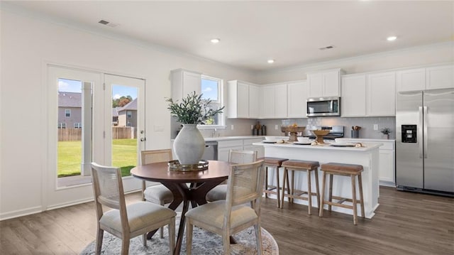 dining space with crown molding, plenty of natural light, and dark hardwood / wood-style floors