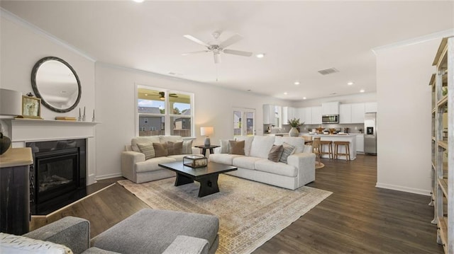 living room featuring dark wood-type flooring, ceiling fan, and crown molding