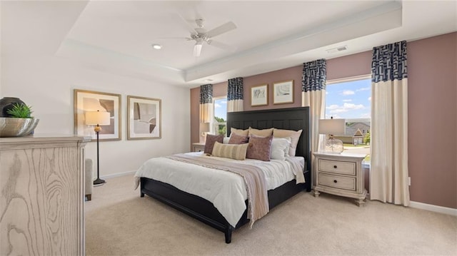 carpeted bedroom featuring a raised ceiling, ceiling fan, and multiple windows