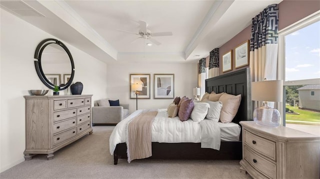 carpeted bedroom with a tray ceiling, multiple windows, and ceiling fan