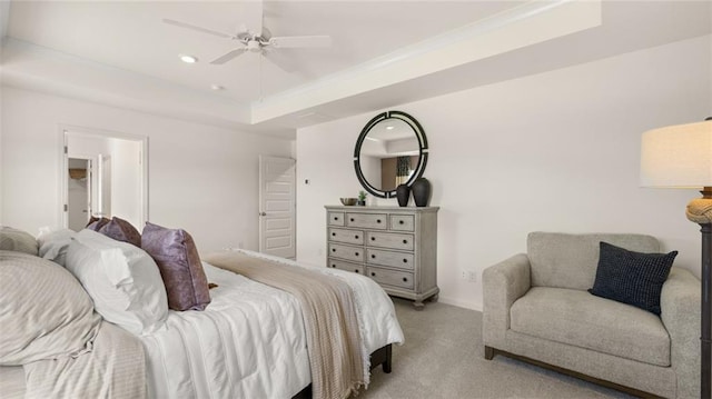 bedroom with ceiling fan, a raised ceiling, and light carpet