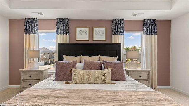 bedroom featuring light colored carpet and a tray ceiling