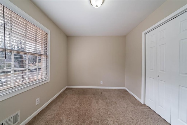 unfurnished bedroom featuring a closet and light carpet