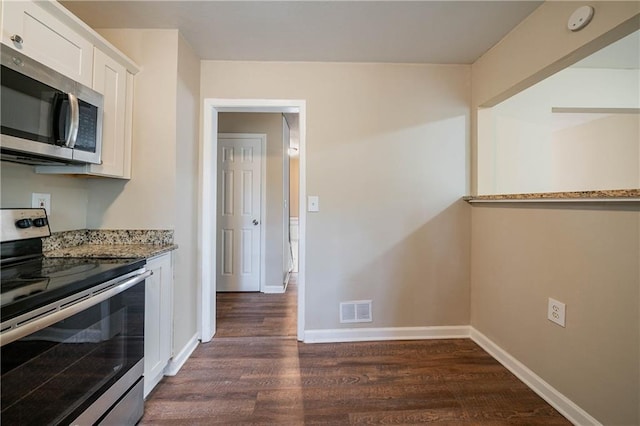 kitchen with light stone counters, white cabinetry, dark hardwood / wood-style flooring, and stainless steel appliances