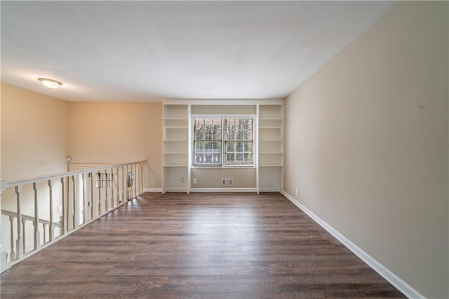 unfurnished room featuring built in shelves and dark hardwood / wood-style floors