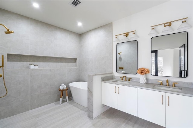 bathroom with visible vents, a sink, tile walls, and double vanity