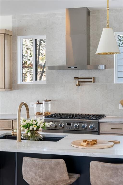 kitchen with wall chimney range hood, a wealth of natural light, pendant lighting, and backsplash