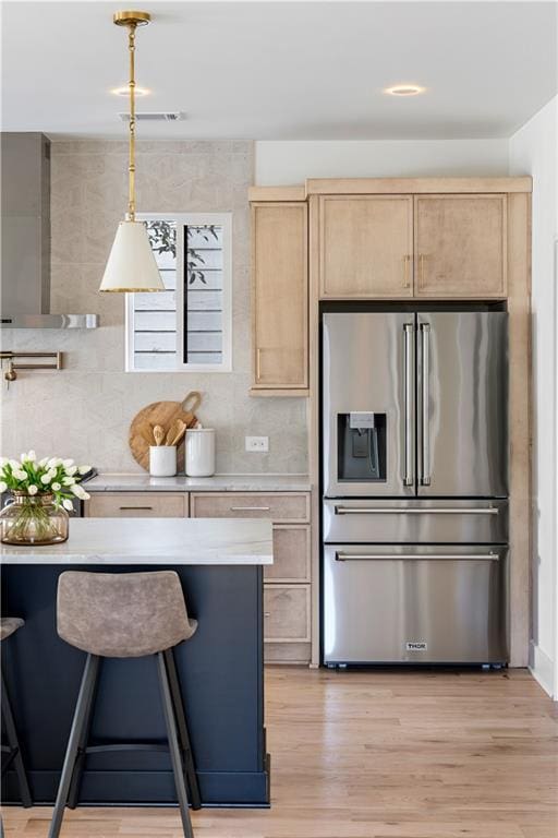 kitchen featuring light countertops, high quality fridge, hanging light fixtures, and light brown cabinets