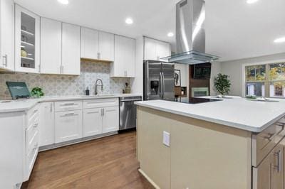 kitchen featuring island exhaust hood, stainless steel appliances, sink, white cabinets, and a kitchen island