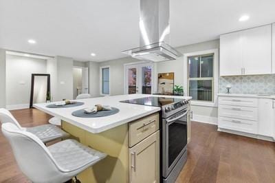 kitchen featuring dark wood-type flooring, electric stove, a kitchen island, white cabinetry, and extractor fan