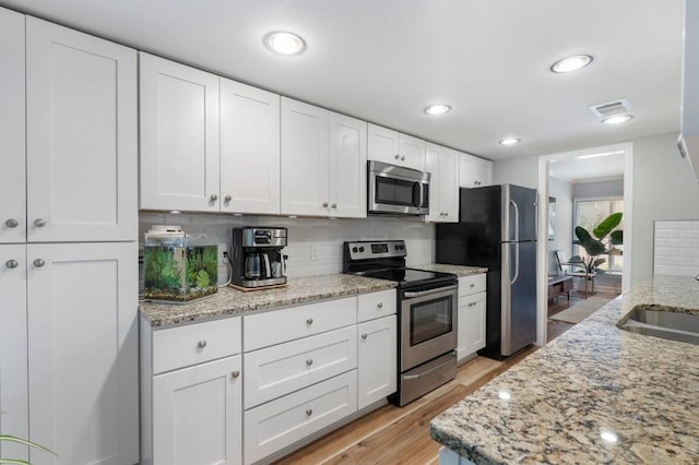 46 Ivy Rdg NE, Atlanta, GA 30342 - kitchen featuring appliances with stainless steel finishes, backsplash, white cabinetry, light wood-style flooring, and light stone counters