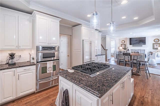 kitchen with light wood finished floors, open floor plan, appliances with stainless steel finishes, white cabinets, and a warming drawer