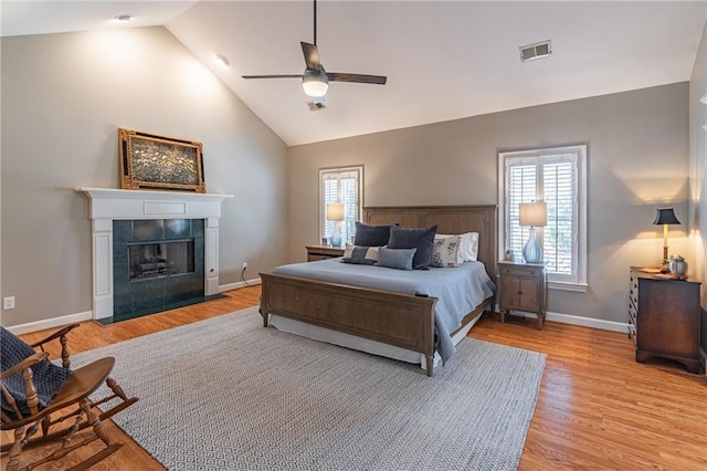 bedroom with baseboards, light wood-style floors, visible vents, and a tile fireplace