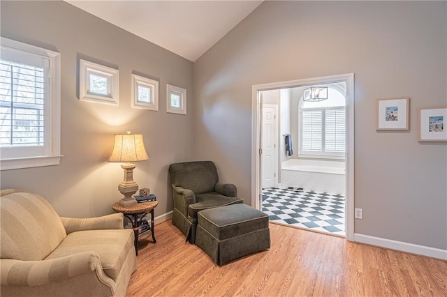 living area with wood finished floors, baseboards, and vaulted ceiling