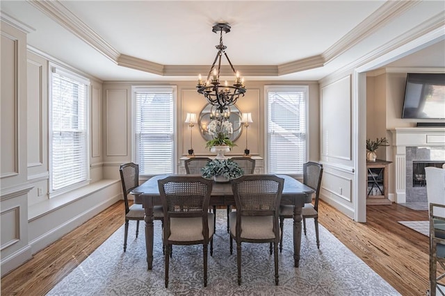 dining space with a raised ceiling, a notable chandelier, and a decorative wall