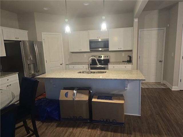 kitchen with an island with sink, stainless steel appliances, dark hardwood / wood-style floors, and hanging light fixtures