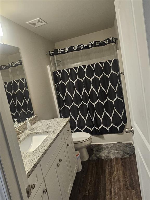 full bathroom with shower / tub combo, hardwood / wood-style flooring, vanity, and toilet