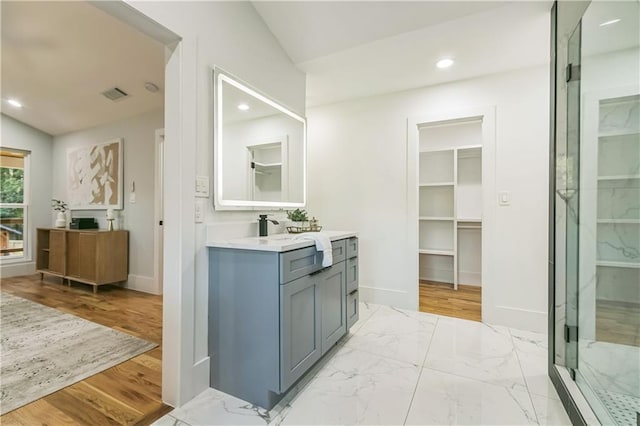 bathroom featuring lofted ceiling, a shower with door, and vanity