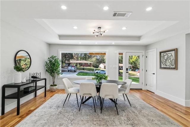 dining area with a tray ceiling and light hardwood / wood-style floors