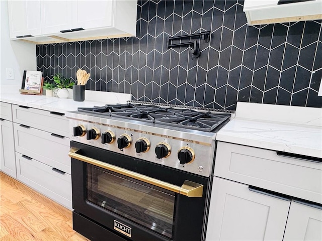 kitchen featuring light hardwood / wood-style flooring, white cabinetry, backsplash, and high end range