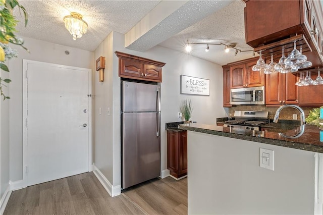 620 Peachtree St NE Unit 911, Atlanta, GA 30308 - kitchen featuring appliances with stainless steel finishes, wood finished floors, backsplash, a textured ceiling, and dark stone counters