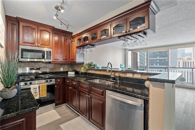 620 Peachtree St NE Unit 911, Atlanta, GA 30308 - kitchen featuring appliances with stainless steel finishes, a textured ceiling, light wood finished floors, a peninsula, and dark stone counters