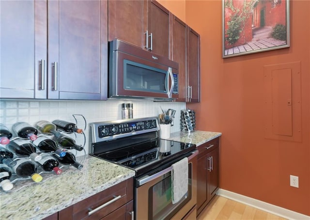 kitchen featuring backsplash, electric range oven, light stone counters, and light hardwood / wood-style floors