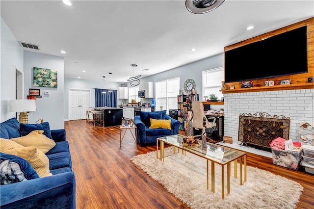 living room featuring wood-type flooring and a brick fireplace