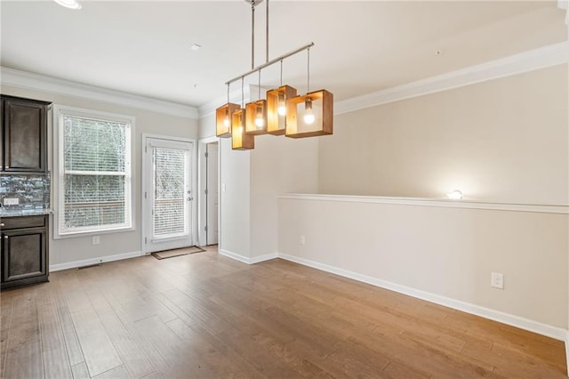 unfurnished dining area featuring ornamental molding and light wood-type flooring