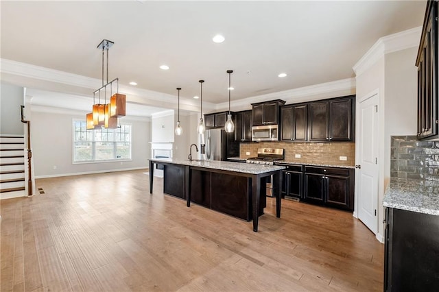 kitchen with a kitchen bar, light stone countertops, hanging light fixtures, and appliances with stainless steel finishes