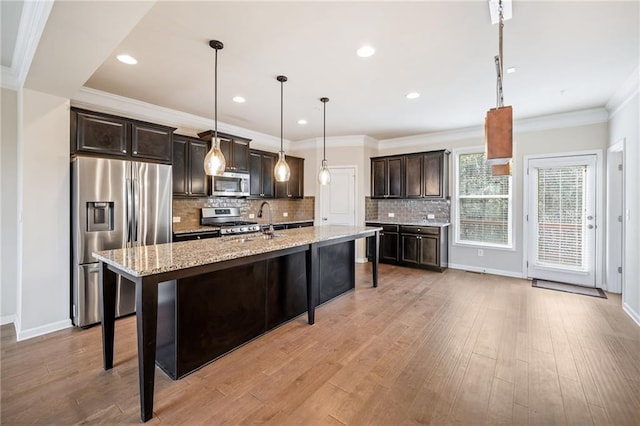 kitchen with pendant lighting, dark brown cabinetry, a kitchen bar, stainless steel appliances, and an island with sink