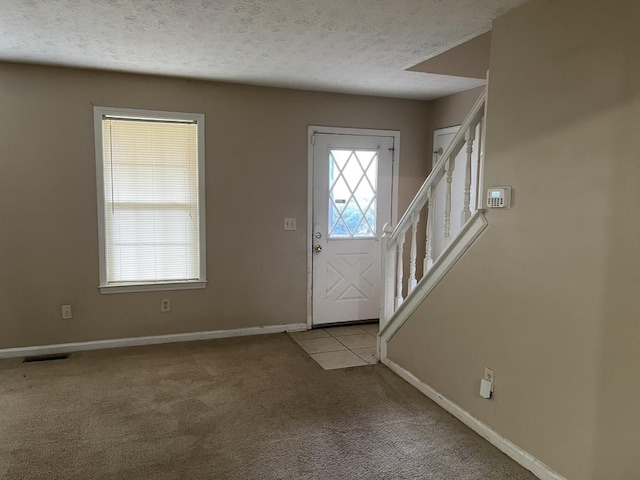 foyer entrance with light colored carpet and a textured ceiling