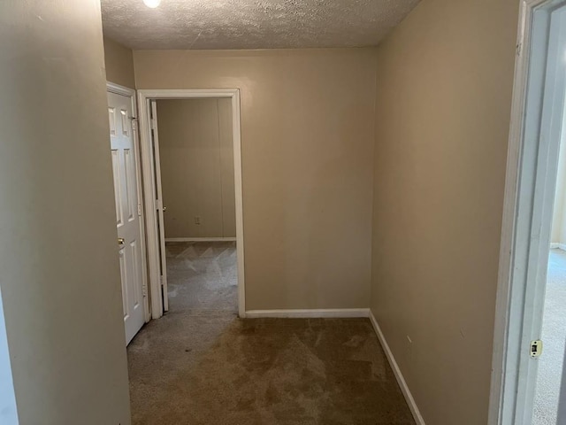 hallway with a textured ceiling and carpet flooring