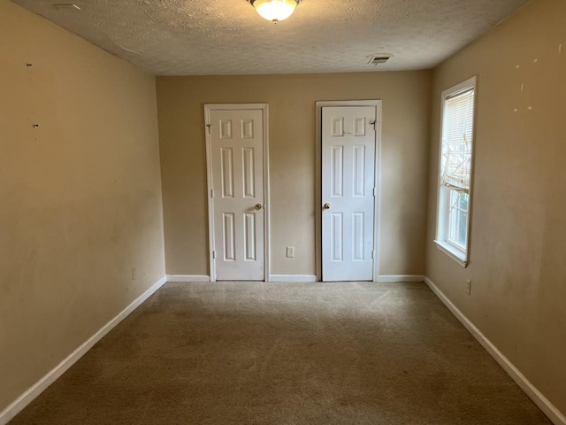 unfurnished bedroom with multiple windows, a textured ceiling, and carpet floors