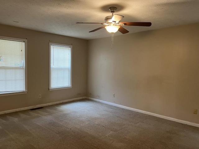 empty room featuring ceiling fan, a textured ceiling, and carpet flooring